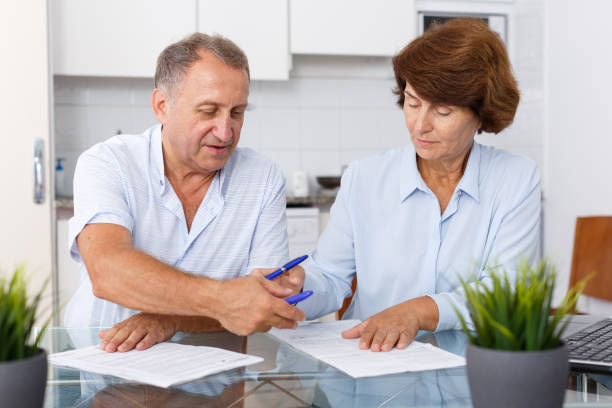 istock Mature family couple sitting at kitchen table and  signing documents 1126103107
