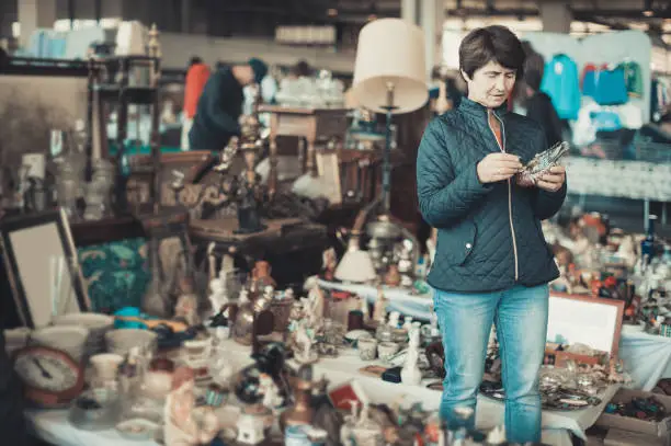 american female is visiting the market of old things and shopping outdoors.