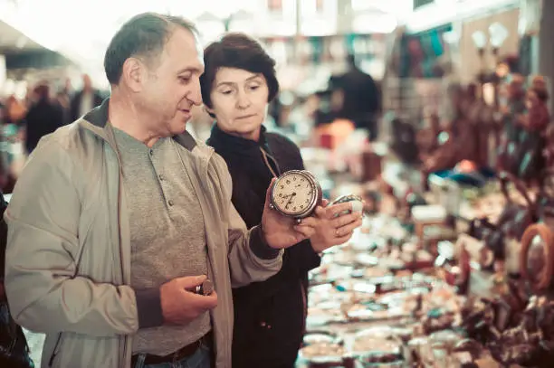 positive american adult man and woman are looking antiquariat at the market of old things