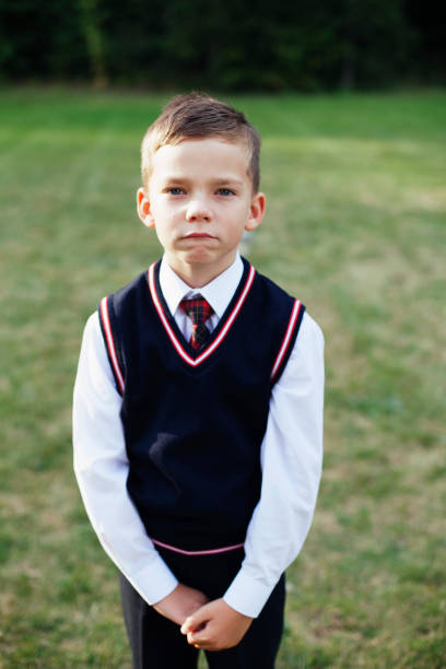 istock A boy dressed up in formal clothes is posing and looking at camera while having his hands clasped. 1126105336