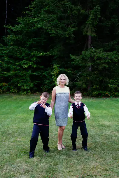 Vilnius, Lithuania - September 1, 2015: Beautiful mother and two boys in their formal clothing are posing for a portrait on the back lawn in summer.