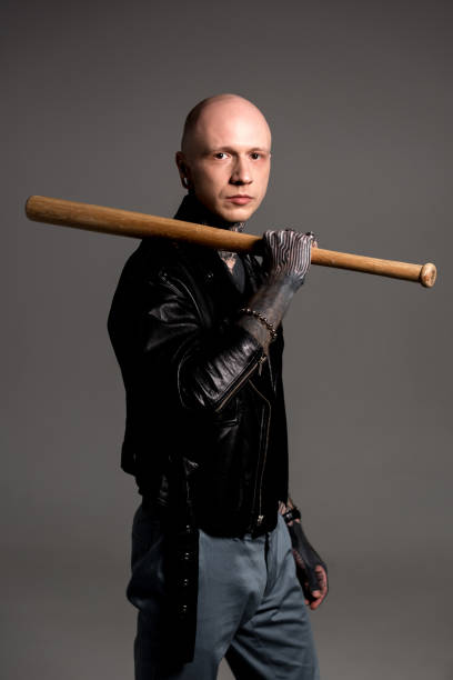 istock stylish bald man with tattoos holding baseball bat and looking at camera isolated on grey 1126105624