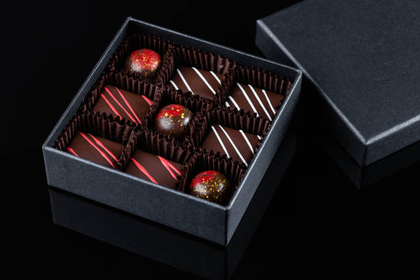 assortment of luxury bonbons with red splashes in box on black background - craft chocolate candy black box imagens e fotografias de stock