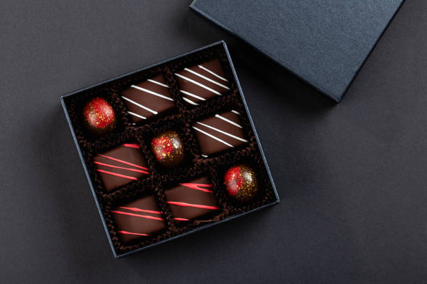 assortment of luxury bonbons with red splashes in box on black background - craft chocolate candy black box imagens e fotografias de stock