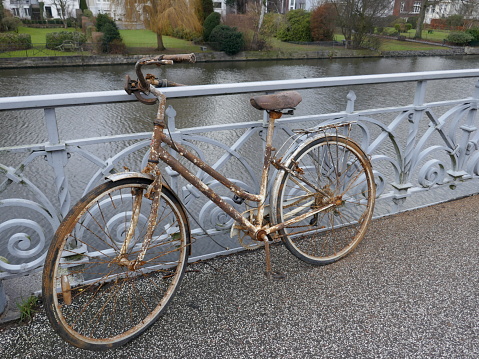 Old rusty lady's bicycle, parked at a bridge railing and then forgotten.