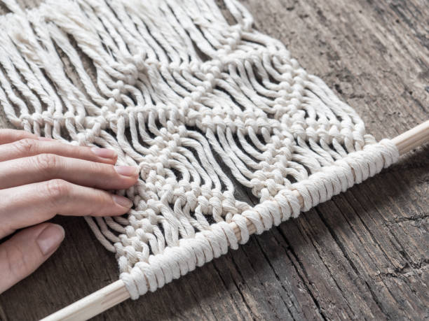 istock Macrame. Girl weaves macrame. White thread, female hand, wooden background, closeup 1126113014