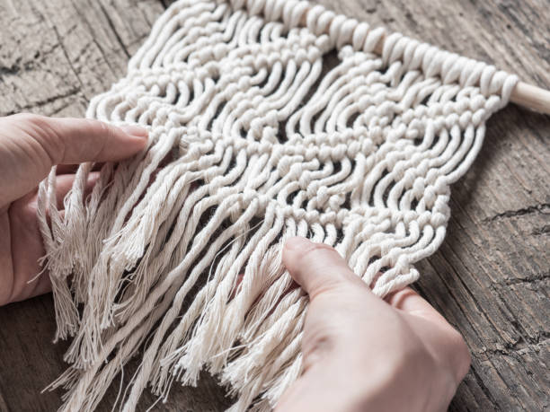 istock Macrame. Girl weaves macrame. White thread, female hand, wooden background, closeup 1126113016
