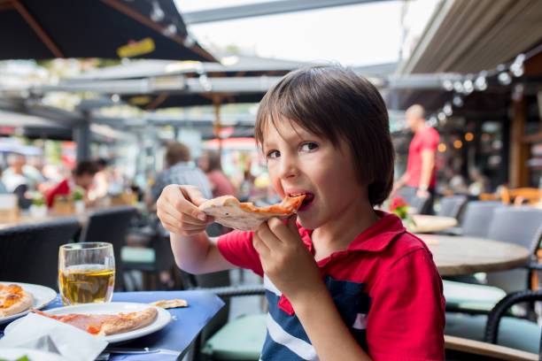 istock Cute child, boy, eating pizza in restaurant, happily smiling 1126117477
