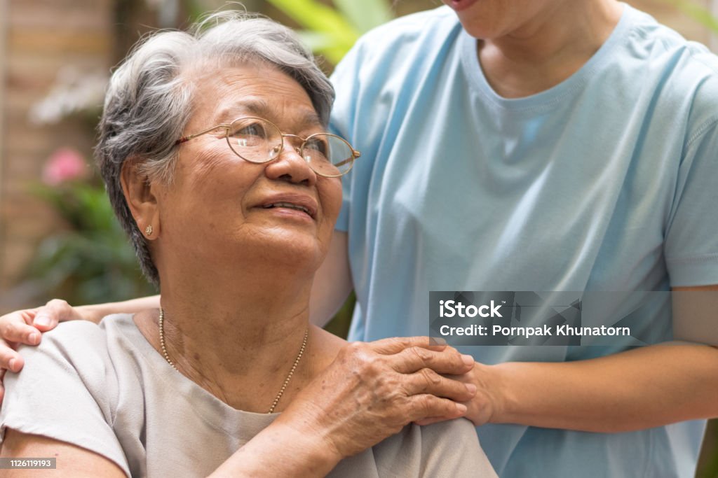 Caregiver, carer hand holding elder hand woman in hospice care. Philanthropy kindness to disabled concept.Public Service Recognition Week Senior Adult Stock Photo