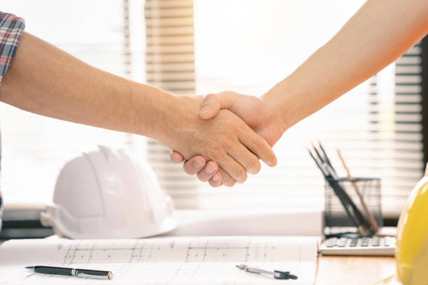 istock architect or civil engineer  and client or customer shaking hands for agreement of home or building plan,plan is fake only for stock photo. 1126125262