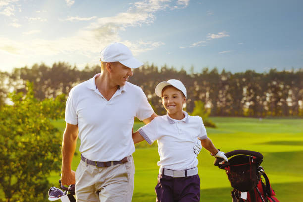 man with his son golfers walking on golf course stock photo