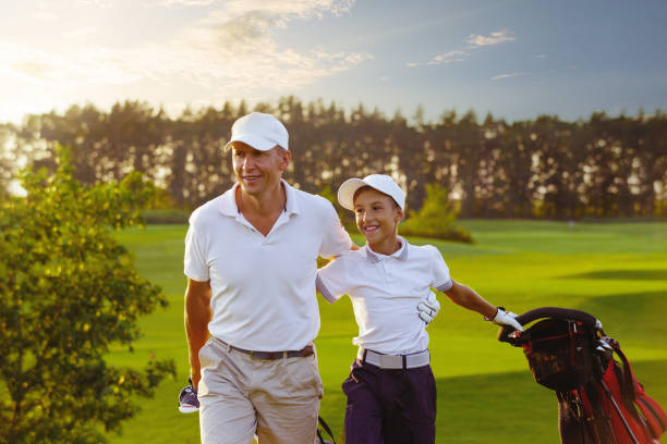 man with his son golfers walking on golf course stock photo