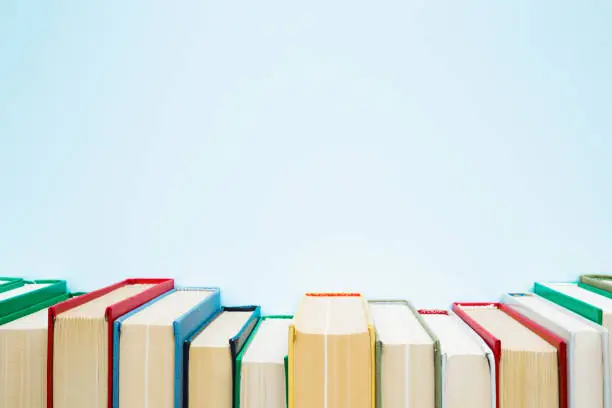 Photo of Row of old books with colorful covers on pastel blue background. Education concept. Mock up for different ideas. Empty place for text, quote or sayings.