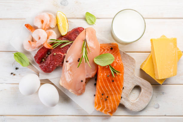 Selection of aminal protein sources on wood background Selection of aminal protein sources - beef, chicken, salmon, cheese, milk, eggs, shrimps on wood background chicken eggs fish stock pictures, royalty-free photos & images