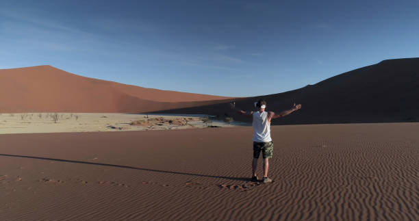 istock Man opening arms on Namibian dunes. Exploring virtual reality 1126136795