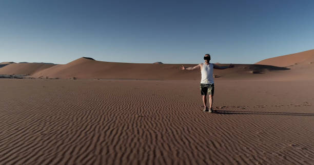 istock Man opening arms on Namibian dunes. Exploring virtual reality 1126136836