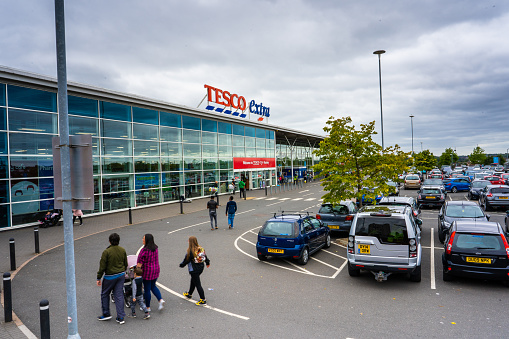 Shoppers head to the large Tesco Express store, shop in Hanley, Stoke on Trent, carpark view with signage