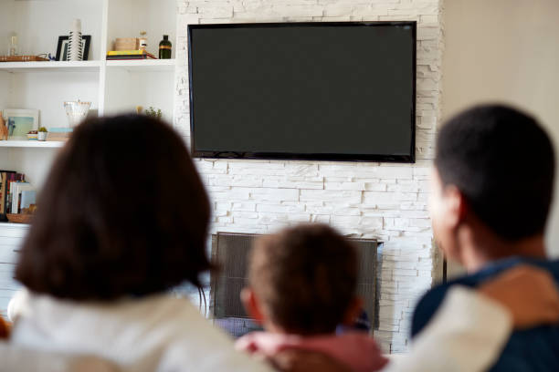 ソファーに坐っている若い家族の背面と、リビング ルームのテレビを一緒に見て、クローズ アップ、テレビに焦点を当てる - child looking blank offspring ストックフォトと画像