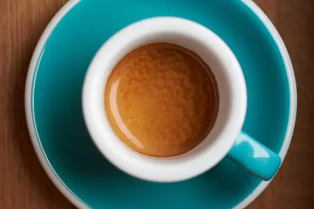 Top view of a wonderful shot of espresso coffee in a teal, thick walled, espresso cup. The coffee has rich crema and a wavy look. The coffee is made from single origin Ethiopia beans that are freshly roasted by a specialty coffee roaster.