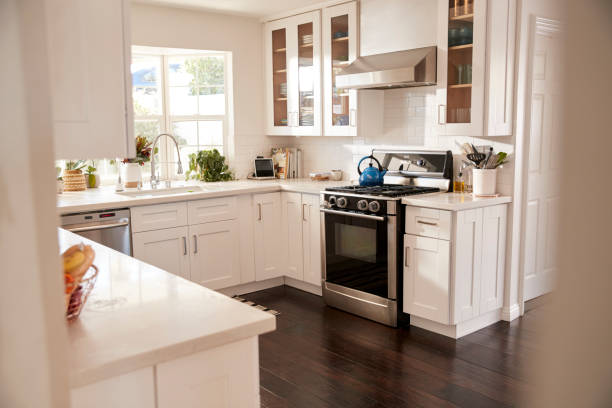 cocina doméstica familiar con muebles blancos y piso madera oscuro, visto desde la puerta - range hood fotografías e imágenes de stock