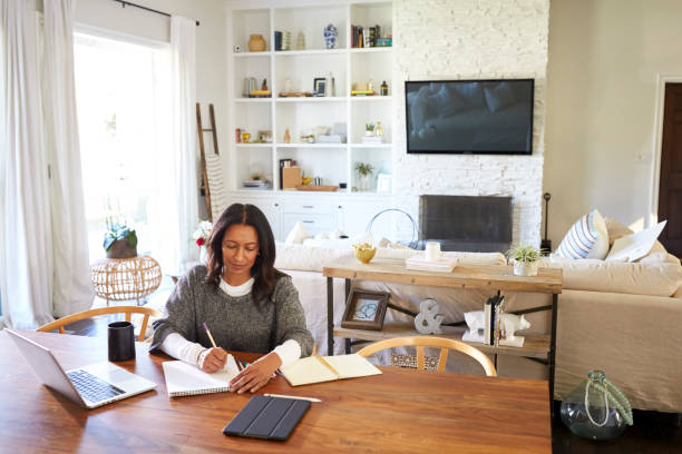 istock Happy middle aged mixed race woman sitting at table in her dining room making notes, elevated view 1126141726