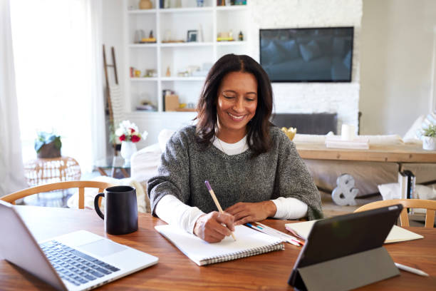 istock Happy middle aged mixed race woman sitting at table in her dining room making notes, selective focus 1126141728