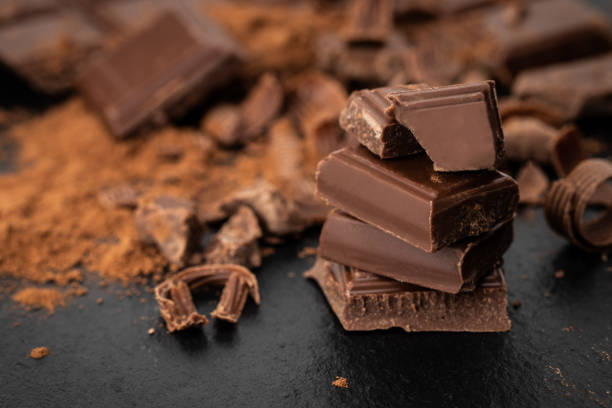 istock Broken chocolate pieces and cocoa powder on a dark background 1126144804