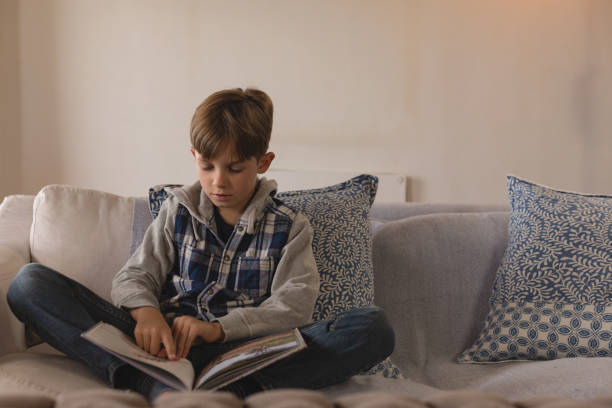 istock Boy reading a story book in living room 1126150681
