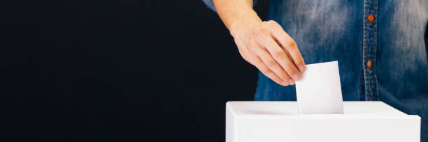 vue de face de la personne qui détient la voix prépondérante de bulletin de vote papier dans un bureau de vote pour le vote de l’élection sur fond noir - alternative medicine audio photos et images de collection