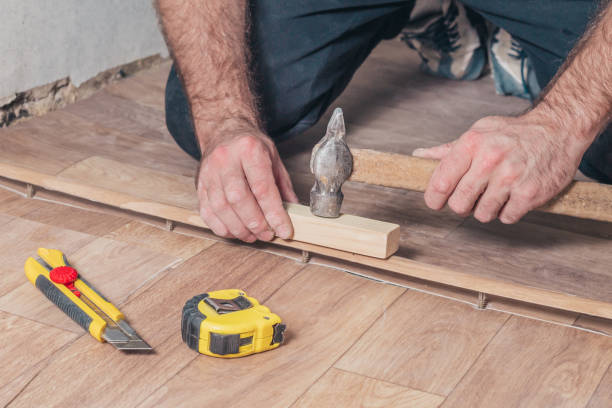 istock Master Class for the installation and installation of floor thresholds - the master hammering the threshold to the floor with a hammer 1126154165