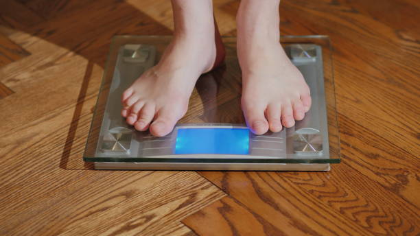 istock A barefoot man measures his weight on a floor scales 1126154566
