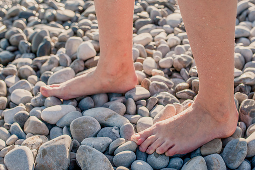 Female feet barefoot on the coastal sea pebble beach