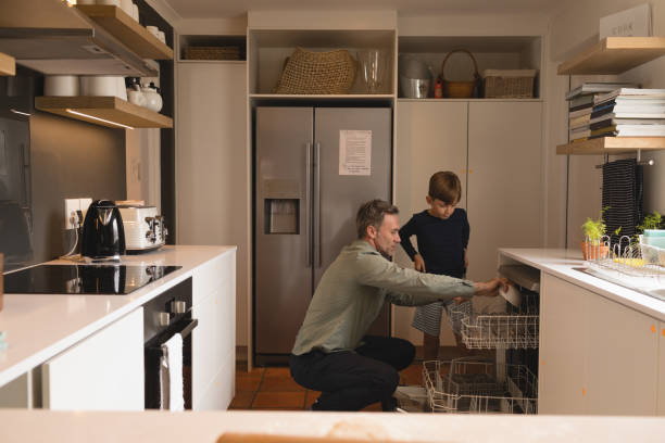 istock Father and son arranging utensils in dishwasher 1126163990
