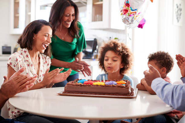 pre teen chica soplando las velas de pastel, sentado a la mesa en la cocina con su familia de tres generaciones, enfoque selectivo - cake birthday domestic kitchen child fotografías e imágenes de stock