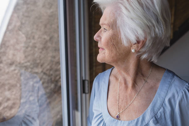 istock Senior woman looking through window 1126178895