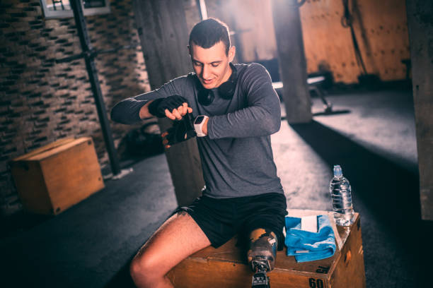 istock Young handicapped athlete putting his training gloves on while preparing for training on a gym box 1126179355