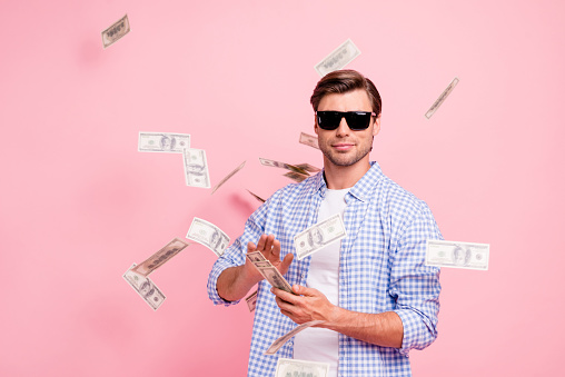 Retrato de su cool moda contenido atractivo guapo sincero chico usar comprobado camisa de tirar el dinero en abundancia de parte de aire aislado sobre fondo rosa pastel photo