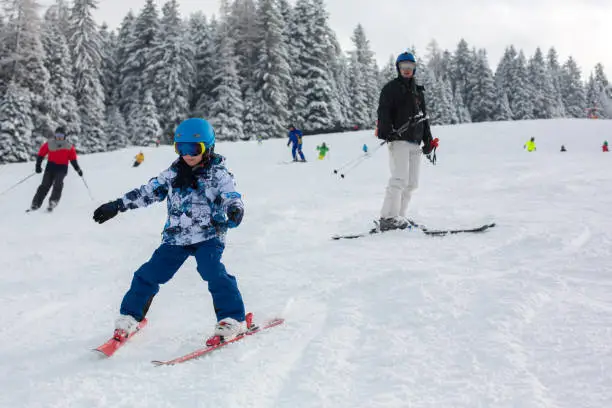 Father and child, skiing together in Austrian resort, winter time