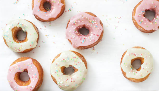 istock Homemade donuts decorated with colored icing and colored sugar on a light background. 1126187907