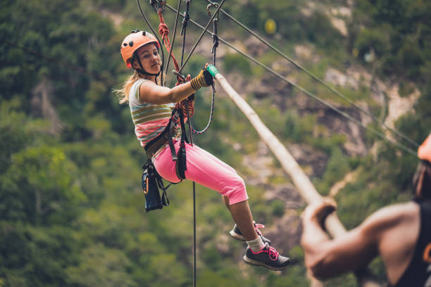smiling young hiker woman climbing obstacle course in the forest, looking at camera and enjoying adventure time.