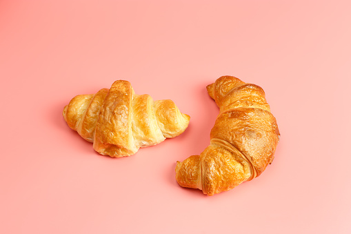 Freshly baked croissants on a pink background.