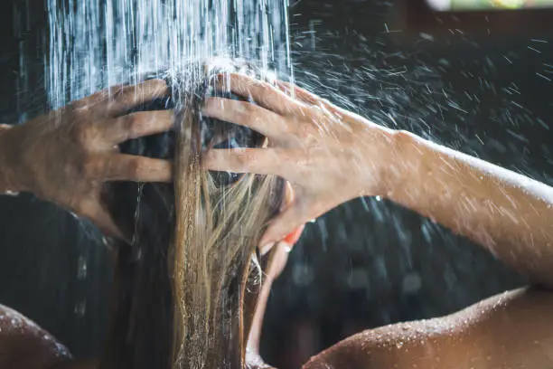 Photo of Close up of a woman washing her hair while showering in the morning.