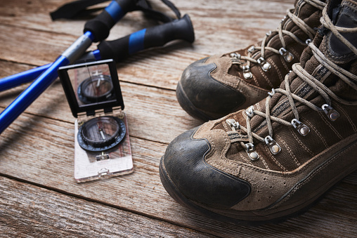 overhead view of hiking boots, compass, and hiking poles.