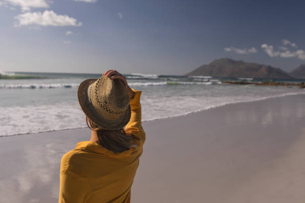 istock Woman in hat standing on the beach 1126195473