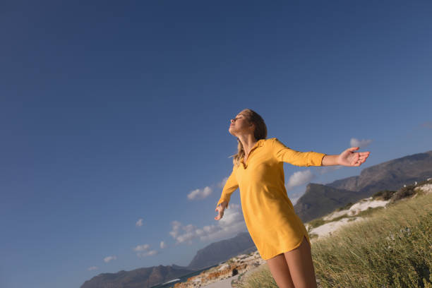 istock Woman standing with arms outstretched on the beach 1126197682