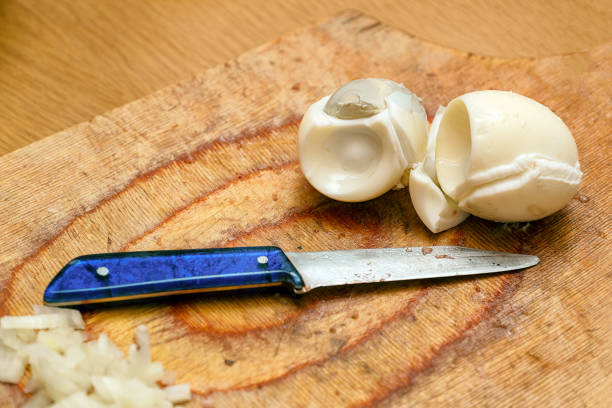 uova sode e un coltello sul tagliere in cucina - hard cooked egg foto e immagini stock