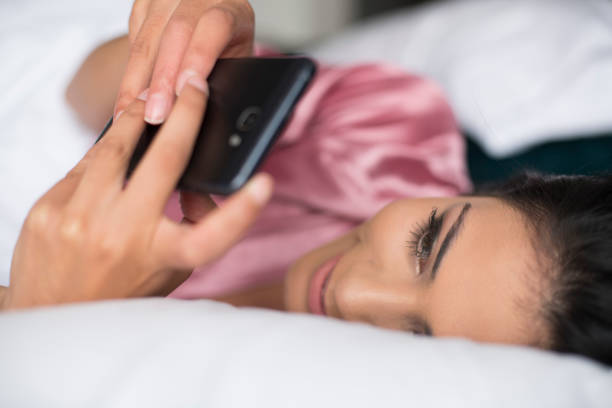 istock woman using her cellphone from the bed 1126200441