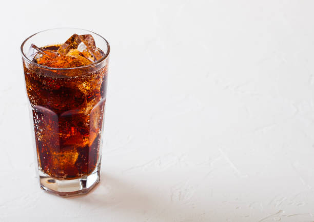 istock Glass of cola soda drink with ice cubes and bubbles on stone kitchen table background. 1126200664