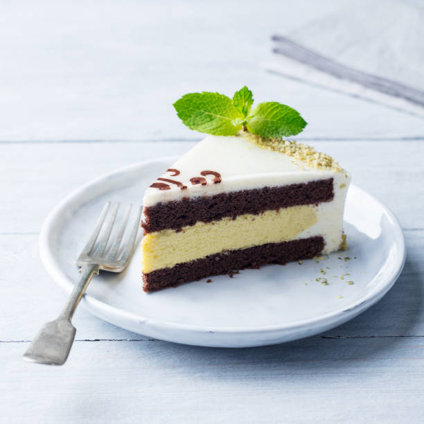 istock White chocolate cake with fresh mint leaf on a plate. Wooden background. 1126202377