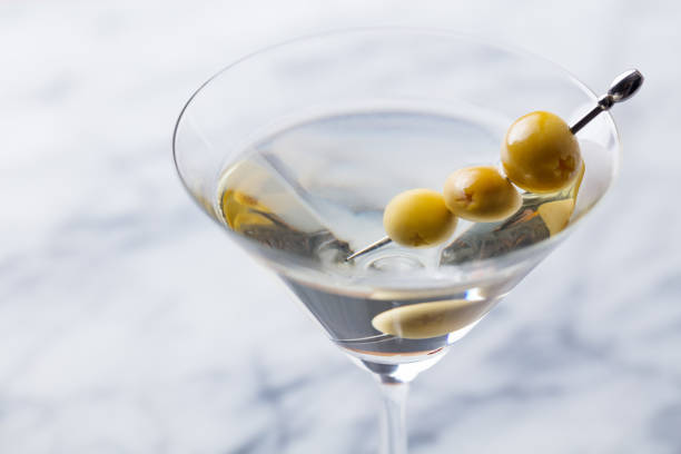 istock Martini cocktail with green olives on marble board. Close up. 1126202954